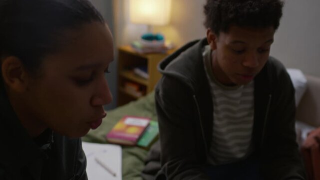 Handheld tilt up shot of young African American female social worker showing brochure to teenage boy, helping him to apply for scholarship for underprivileged students during home visit