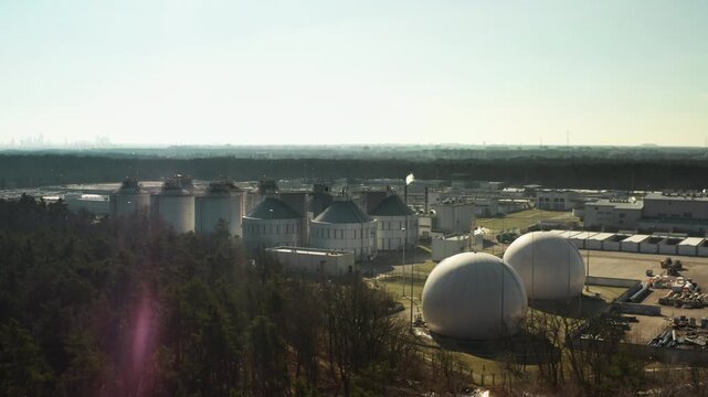 Sludge digester tanks process urban wastewater for the metropolitan area. Large industrial facility produces sustainable biogas and filters city sewage to reduce local ecological pollution.
