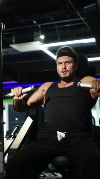 Focused athlete performing a seated chest press on a strength machine in a modern gym, showing muscular effort, motion, and intense concentration under dramatic lighting.