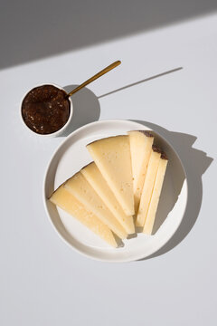 Manchego cheese with fig jam on a white plate