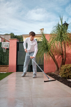 Teen boy cleaning terrace with floor squeegee