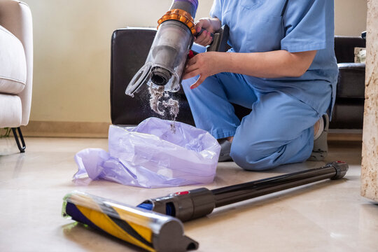 Woman cleaning and emptying vacuum cleaner