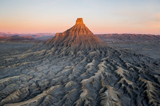 Aerial view of stark, arid land formations sculpted by time under the warm glow of the setting sun, Badlands, Utah, United States.