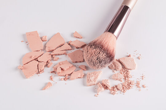Makeup brush with broken compact powder on surface