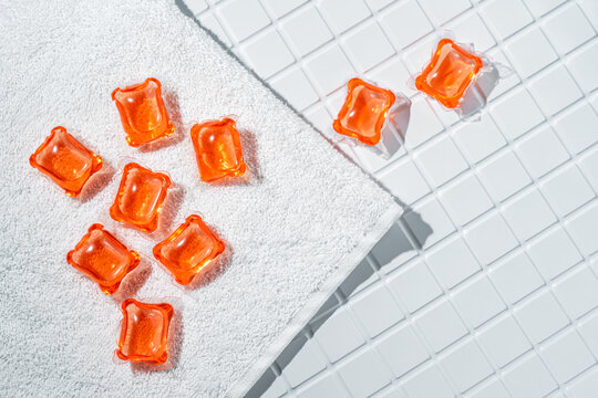 Laundry capsules on white towel and tiled surface