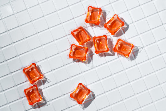Bright orange laundry capsules on white tiles