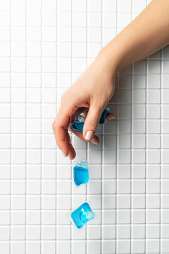 Hand dropping laundry capsules with tiled background