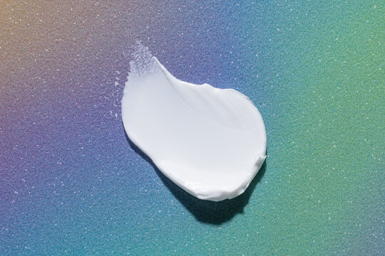 Cosmetic cream smear on a colorful gradient background