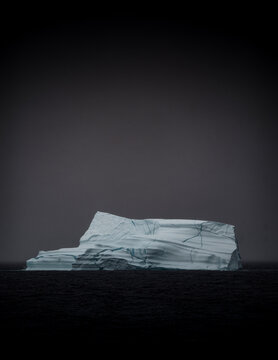 Majestic Arctic iceberg floating under dark skies