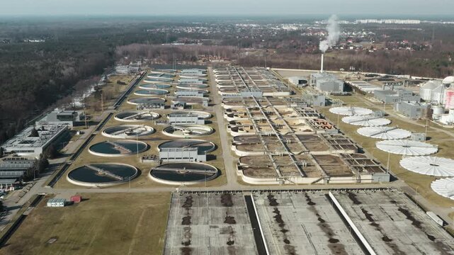 Sewage treatment plant utilizes sludge digester domes and circular clarifiers. Large industrial facility purifies wastewater and produces sustainable biogas from municipal liquid waste.
