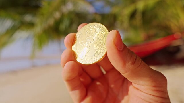 A Hand Holds a Gold Tether USDT Token Over a Sunlit Tropical Beach Highlighting Stable Digital Currency and Modern Blockchain Finance