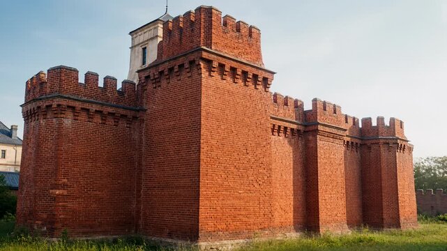 Medieval Castle Fortifications With Red Brick Walls and Crenellations Under a Blue Sky