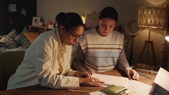 Teen girl finishing solving math problem and showing it to her tutor who checking it and praising her student