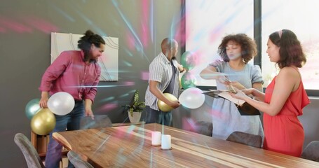 Decorating group of four arranging balloons, papers and candles at meeting table, in casual clothes
