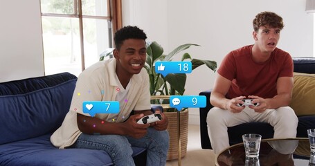 Playing two men holding white controllers on blue velvet sofa in living room with reaction graphics © vectorfusionart