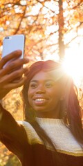 Happy black woman taking selfie in autumn nature