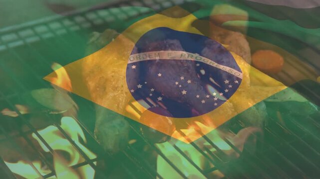 The brazilian flag is shown waving while chicken drumsticks are being cooked on a flaming barbecue