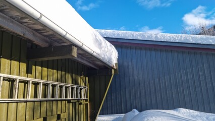 Snow covers roofs in a winter scene with clear blue sky above