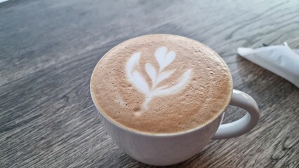 Coffee with latte art on wooden table during morning hours in cafe