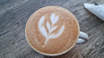 Coffee with latte art in a cup on a wooden table