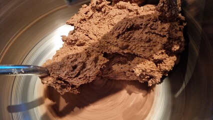 Mixing chocolate dough in a bowl using a metal spoon in a kitchen setting