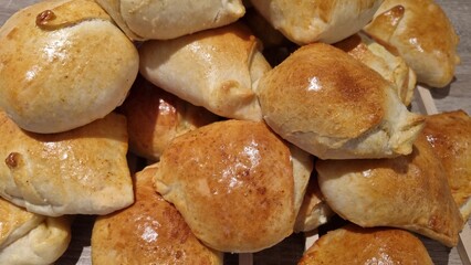 Freshly baked bread rolls on a wooden tray ready for serving at a family meal