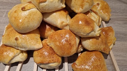 Fresh baked bread rolls stacked on a wooden surface