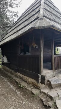 Vertical panoramic view of traditional wooden houses in ethno village Staro Selo in Sirogojno, Serbia. Historic rural architecture surrounded by green hills and blue sky