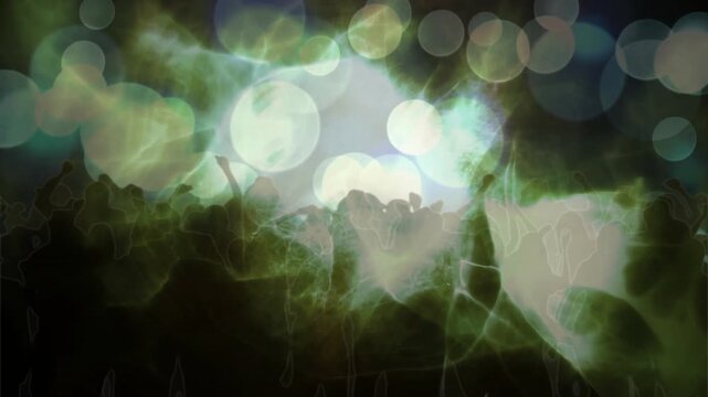 Central light pulsing, shadowed crowd raising hands, lifting phones, reacting to music