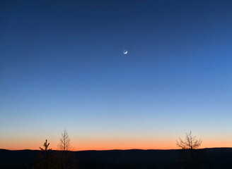 Crescent moon over mountains at sunset with copy space