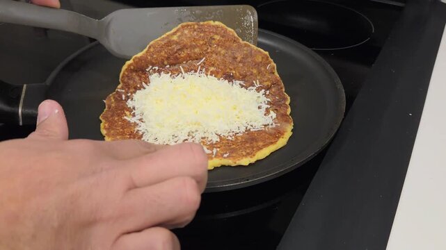 Traditional Venezuelan cachapa being filled with shredded white cheese and folded