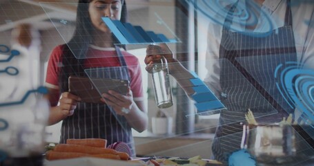 Cooking teen and adult in aprons holding bottle while using tablet in kitchen, carrots, holograms © vectorfusionart