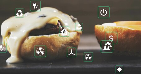 Showing cheeseburger with melted cheese oozing toasted bun and patty on dark table with green icons
