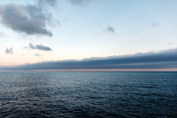 Fototapeta premium Barcelona's vast ocean horizon under a dramatic sky with distant airplane