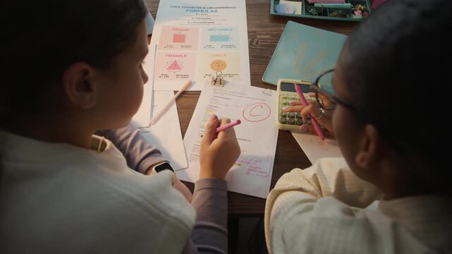 High angle shot of unrecognizable teen student and young math tutor examining paper with checked test and solving math problems together