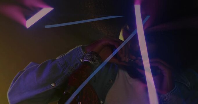 Singer leaning to mic, forming heart sign with music pulsing as neon beams sweeping, crossing frame