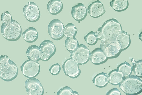 Green cosmetic serum or gel or shampoo on mint background isolated. Beauty product sample swatch