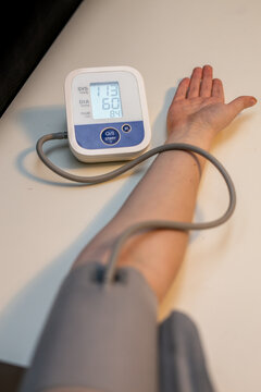 Young person having their blood pressure measured with an automatic upper arm blood pressure monitor. The digital device is used to track blood pressure levels and help monitor hypertension risk