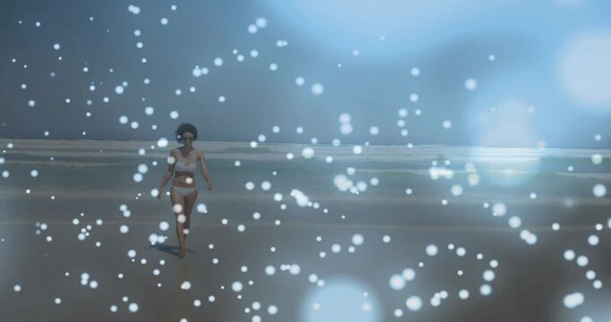 Woman beginning walking from horizon toward camera, travel scene with drifting particles, wet sand