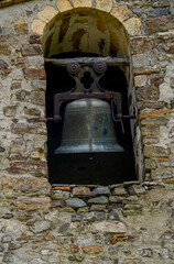 Obraz premium Close-up of ancient bronze bell in stone arch