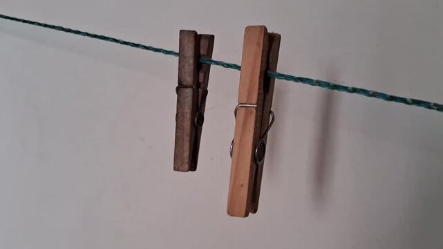 Wooden clothespins hanging on blue rope against white background.