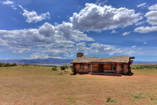 Rustic cabin in open desert landscape under dramatic clouds