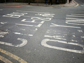 Busy Manchester street with faded bus lane markings on a cloudy day