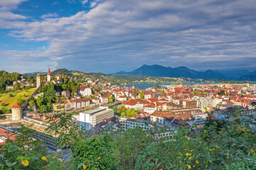 Obraz premium Beautiful view of Lucerne, Switzerland featuring the famous wooden Chapel Bridge with Water Tower over the Reuss River. Scenic cityscape with alpine mountains, clear water, and colorful historic archi