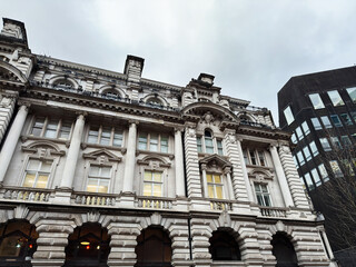 Naklejka premium Historic Manchester building with ornate stone facade and arches beside modern offices in the UK