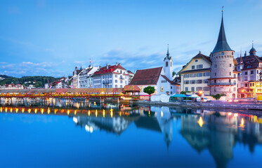 Obraz premium Beautiful view of Lucerne, Switzerland featuring the famous wooden Chapel Bridge with Water Tower over the Reuss River. Scenic cityscape with alpine mountains, clear water, and colorful historic archi