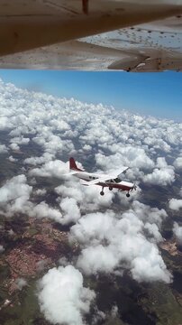 Parachutists jumping from a Cessna Caravan while another plane flies nearby.