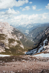 Spectacular panoramic sunset over the Italian Dolomites with the mountain summits glowing in golden light, dramatic clouds over the valley, and a peaceful wilderness landscape in the Alps