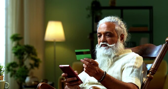 Indian mid age bearded man expressing distress because of online fraud after debit card payment using smartphone at home, stylish mature male feeling frustrated over digital scam and financial theft