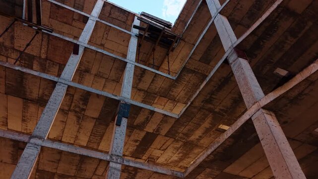 Rising inside the frame of the future building. Metal rebars stick out at the top. Construction concept.